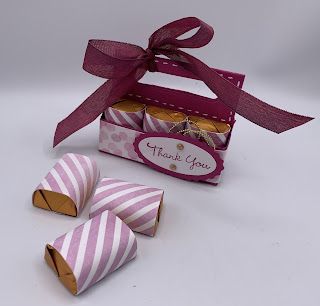 pink and white striped candy boxes with purple ribbon tied around the top, sitting on a white surface