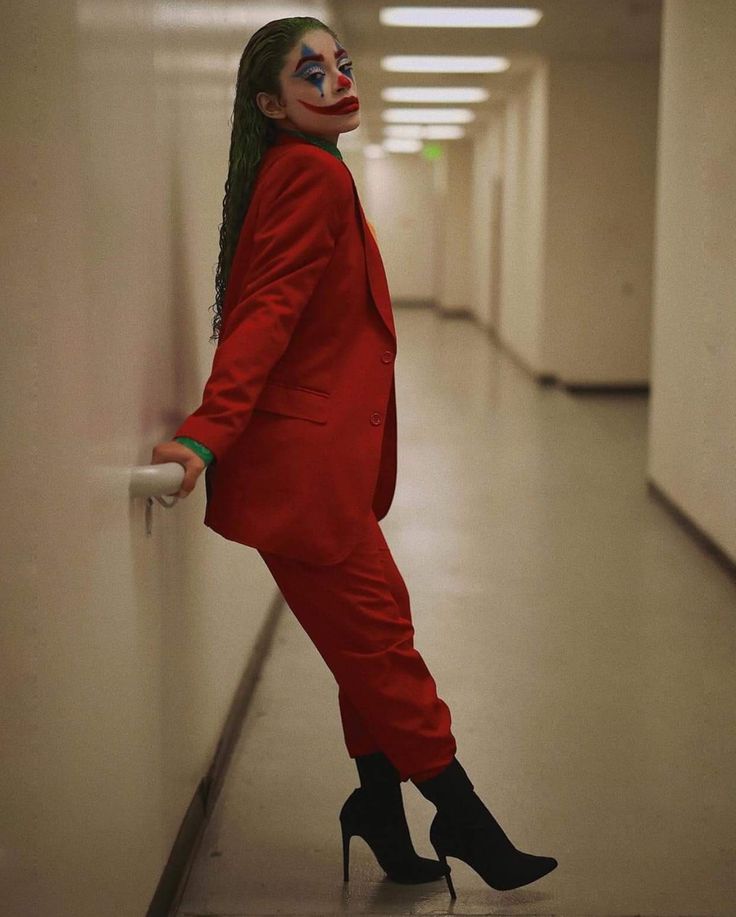 a woman dressed as the joker leaning against a wall