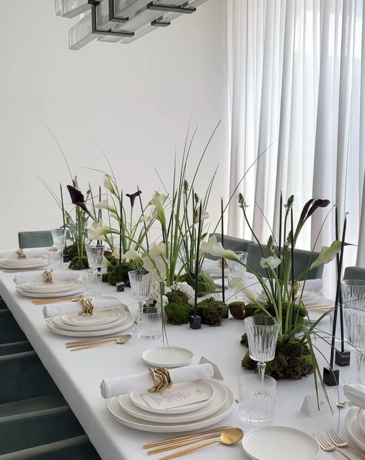 the table is set with white plates and place settings