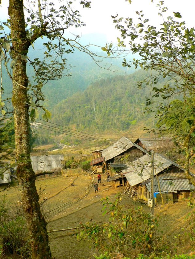 an old village in the mountains surrounded by trees and people walking around it on a cloudy day