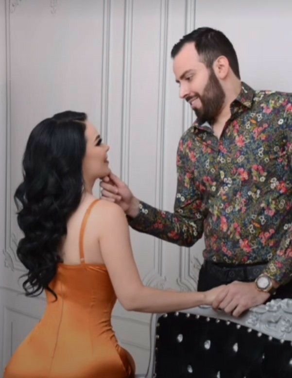 a man and woman standing next to each other in front of a cake