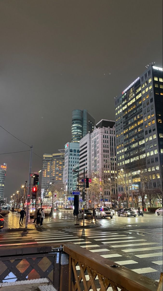 a city street filled with lots of traffic and tall buildings in the background at night