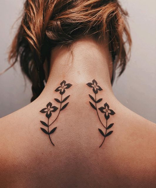 the back of a woman's neck with two flowers on her left and one flower on