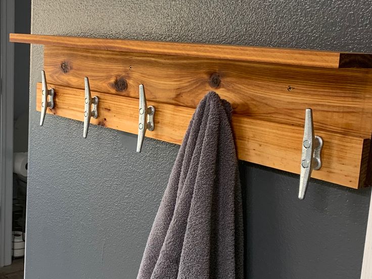 a towel rack with three hooks and two towels hanging on the wall next to it