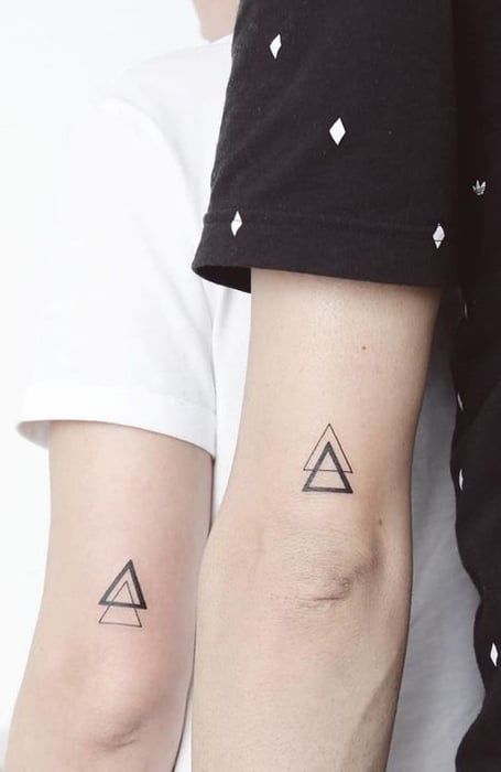 two people with matching tattoos on their arms, one is holding the other's arm