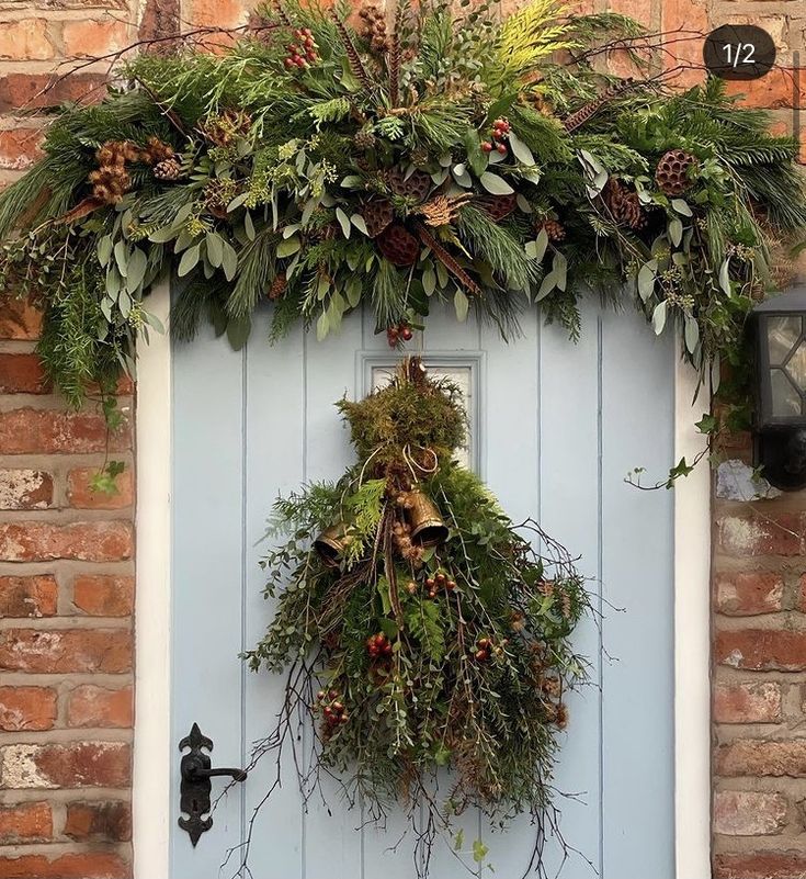 a blue door decorated with greenery and pine cones