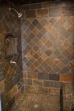 a tiled shower in a bathroom with brown and tan tiles on the wall next to it