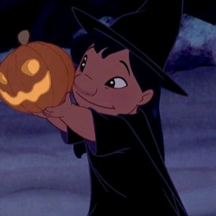 a young boy dressed as a witch holding a jack - o'- lantern in his hand