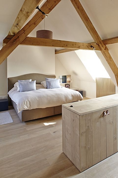 a bedroom with wooden beams and a bed in the corner, on top of a hard wood floor