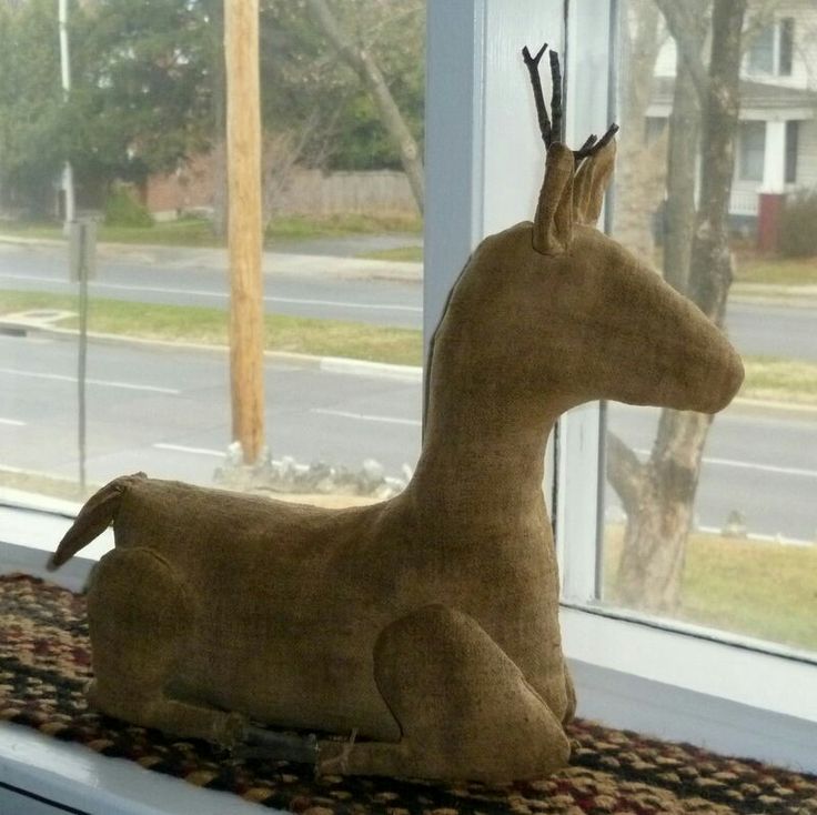 a stuffed deer sitting on top of a window sill