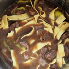 a pot filled with beef and noodles in broth