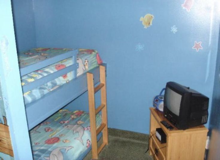 a bedroom with bunk beds and a small tv on top of the dresser next to it