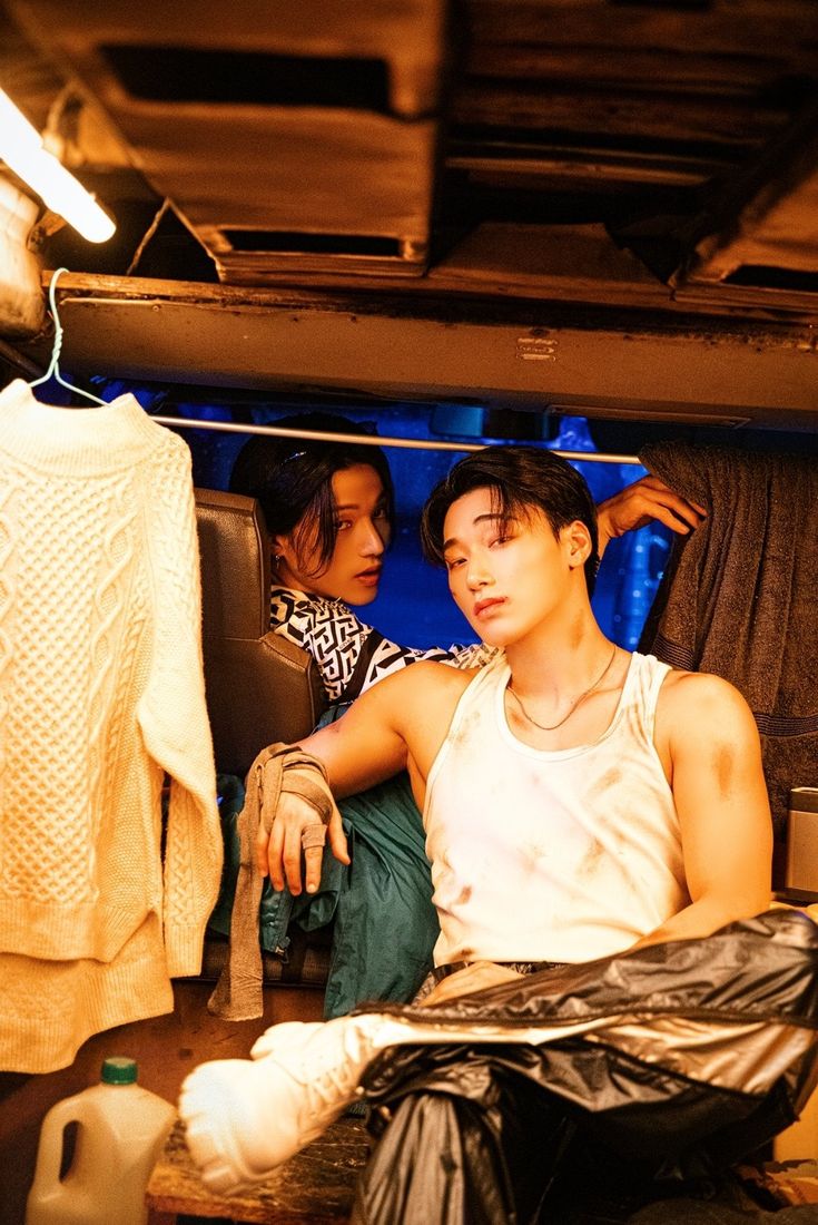 two young men sitting in the back of a truck with clothes hanging up to dry