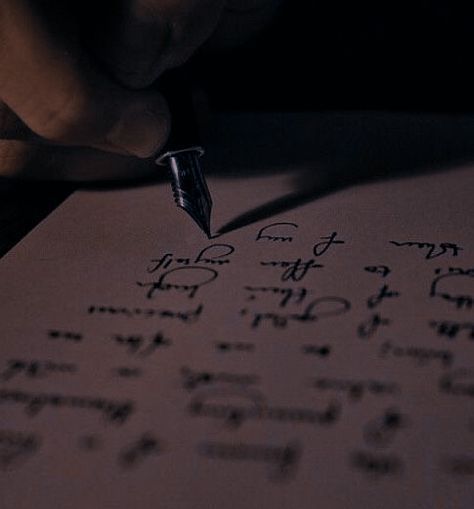 a person writing on paper with a pen