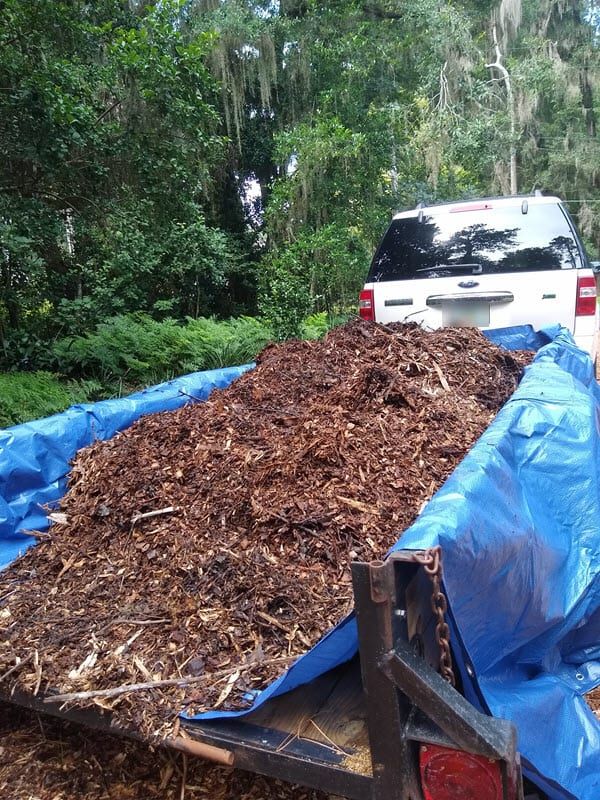 a truck is loaded with wood chips and mulchs in the back, along with a blue tarp