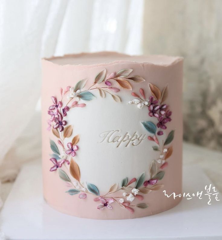 a pink birthday cake decorated with flowers and the word happy on it's side