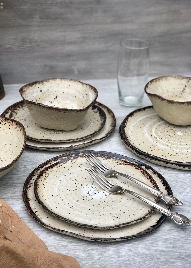 a table topped with plates and silverware on top of a wooden table