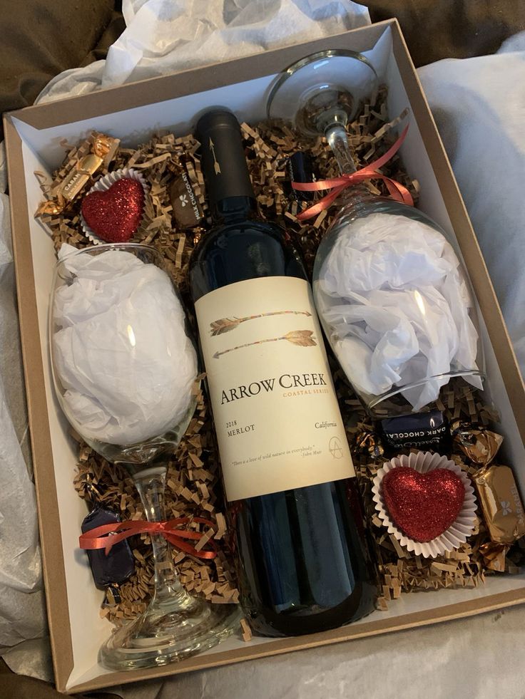 a bottle of wine sitting in a box next to some chocolates and other items