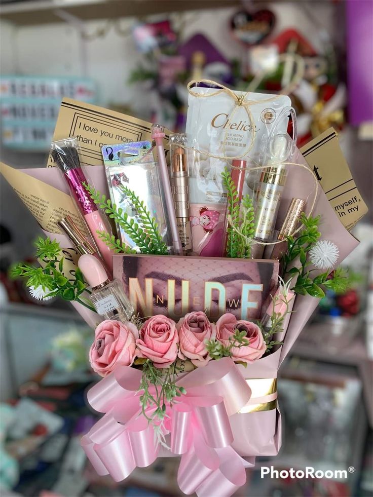 a pink flower arrangement with cosmetics and other items in the center, on top of a table