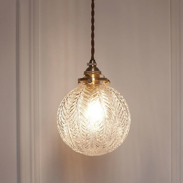 a glass light fixture hanging from a ceiling