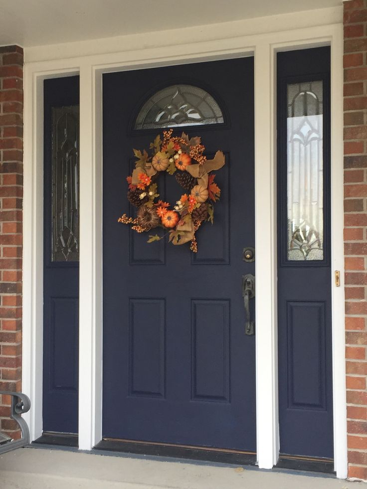 a blue front door with a wreath and pumpkins hanging on it's side