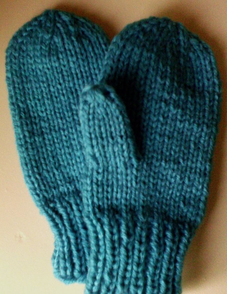 a pair of blue knitted mittens sitting on top of a table