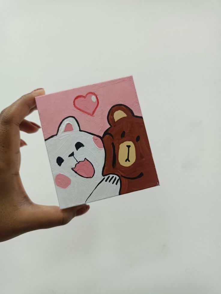 a hand holding up a card with two bears and a bear on it, one has a heart