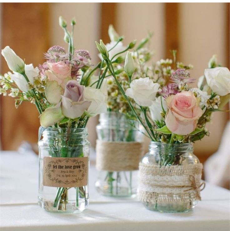 three mason jars with flowers in them are sitting on a table, one is empty