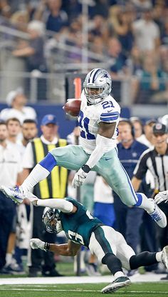 a football player is jumping in the air to catch a ball while people look on