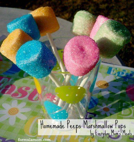 colorful marshmallow lollipops are in a glass vase on a table