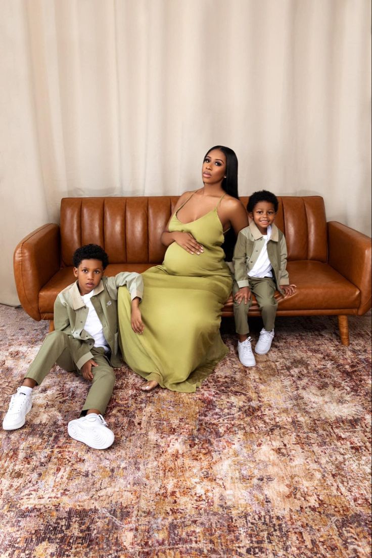 a woman and two children are sitting on the floor in front of a brown couch