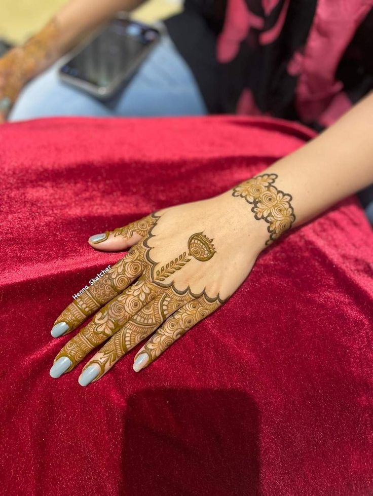 a woman's hand with henna on it sitting on top of a red cloth