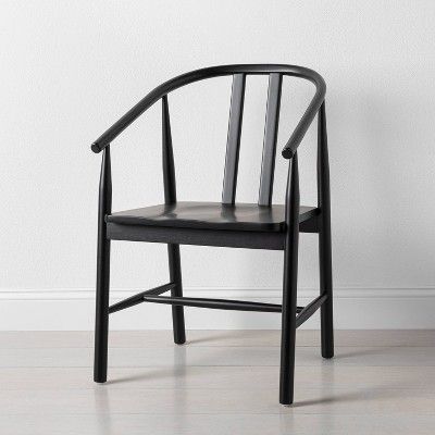 a black wooden chair against a white wall