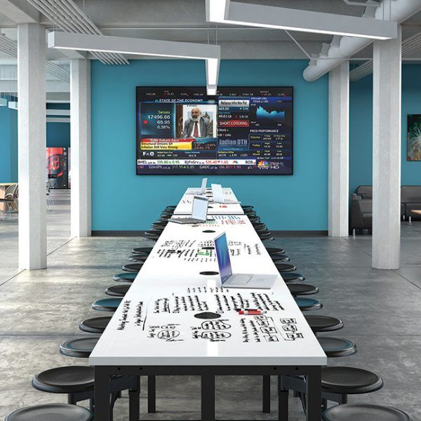 a long table is set up in the middle of a room with blue walls and black chairs