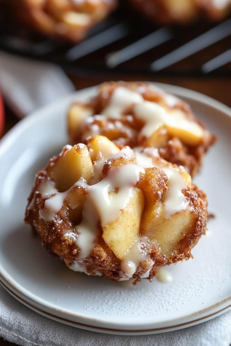 two pastries are sitting on a plate with icing and apples in the background