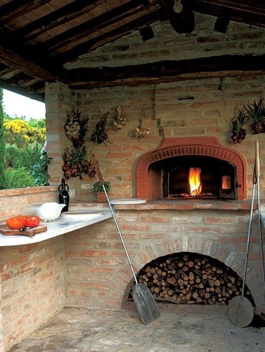 an outdoor oven with fire in it and pots on the stove top next to it