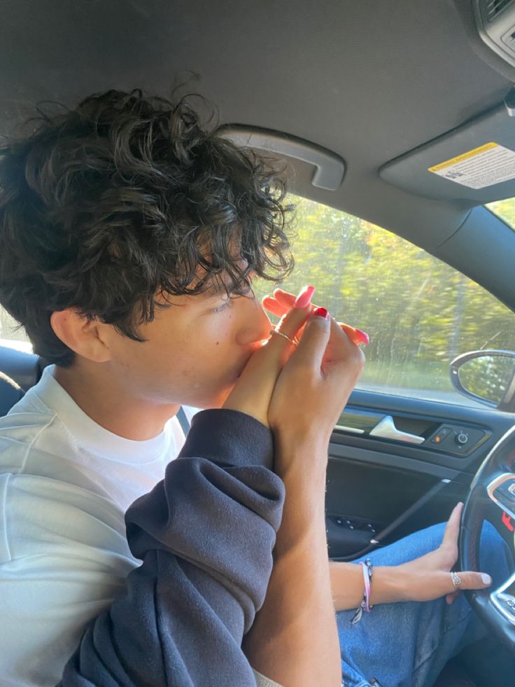 a woman sitting in the passenger seat of a car with her hand on her mouth