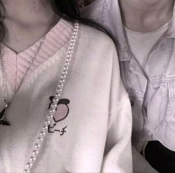 two people wearing sweaters and pearls on their necklaces