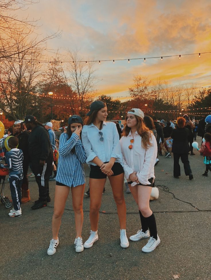 two young women standing next to each other in front of a group of people at an outdoor event