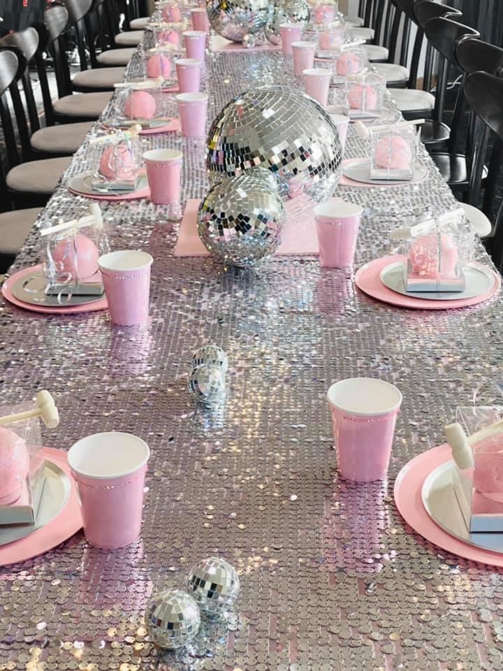 the table is set with pink and silver decorations