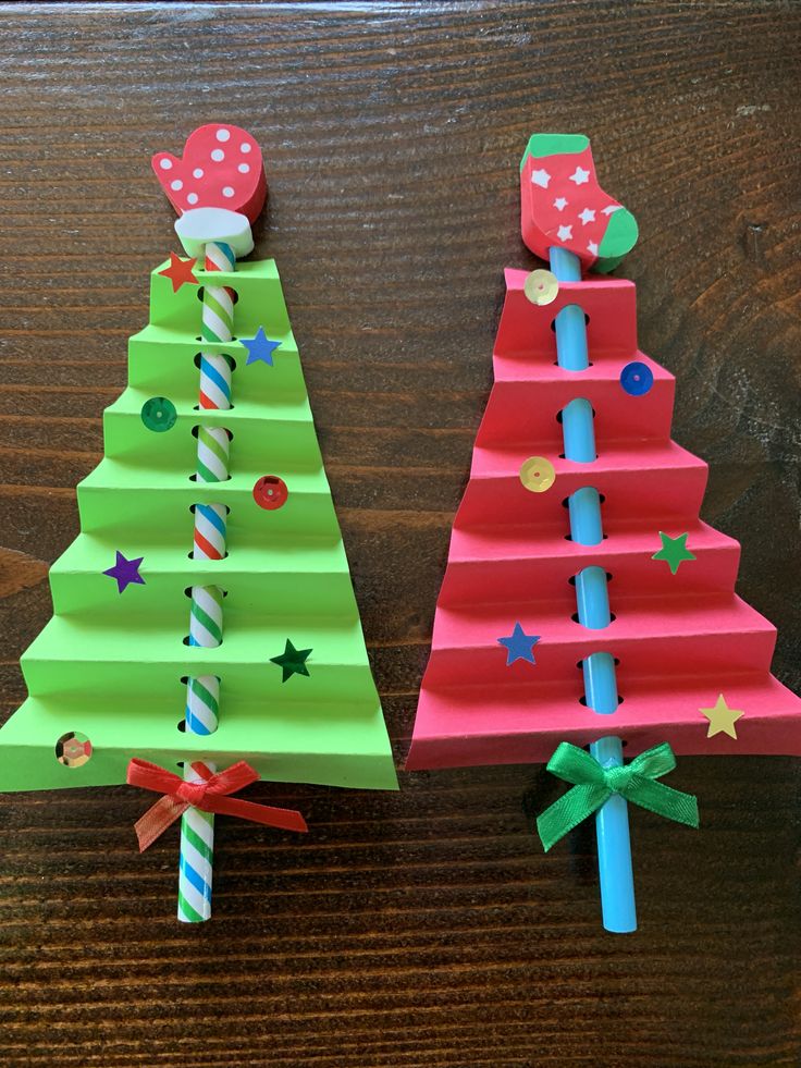 two christmas trees made out of paper sitting on top of a wooden table next to each other