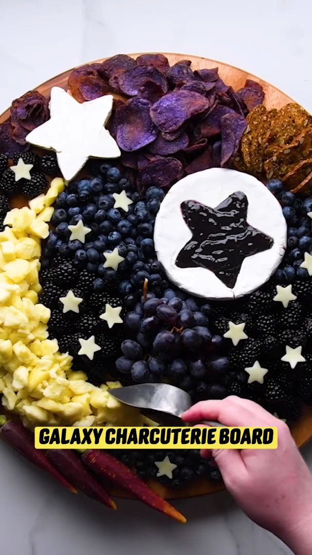 a plate with grapes, cheese and crackers on it that says galaxy cheese board