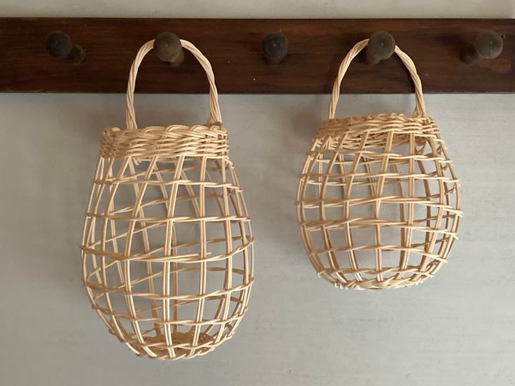 two woven baskets hanging from hooks on a wall