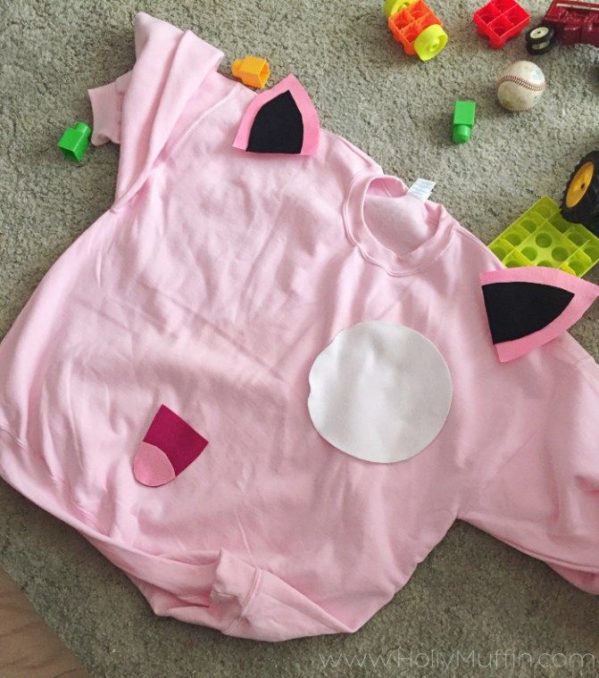 a child's pink shirt laying on the floor next to toys