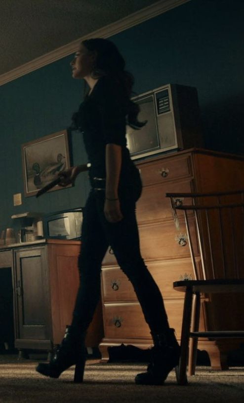 a woman walking through a living room next to a dresser