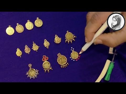 a person is holding a pen and some gold jewelry on a purple surface with a coin in the background