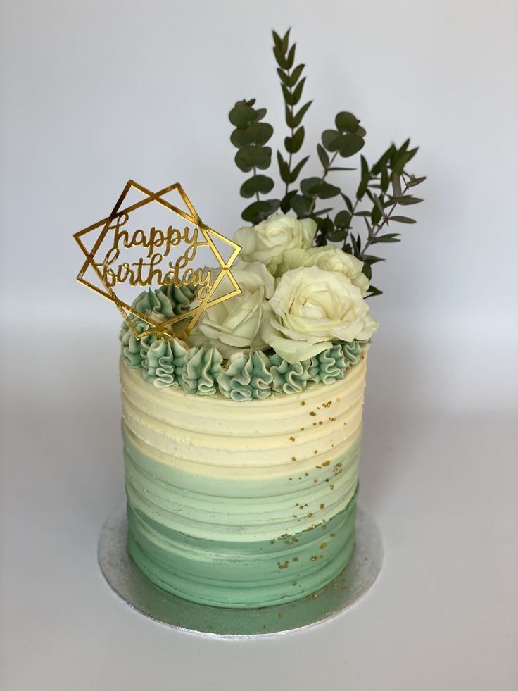 a birthday cake decorated with flowers and greenery