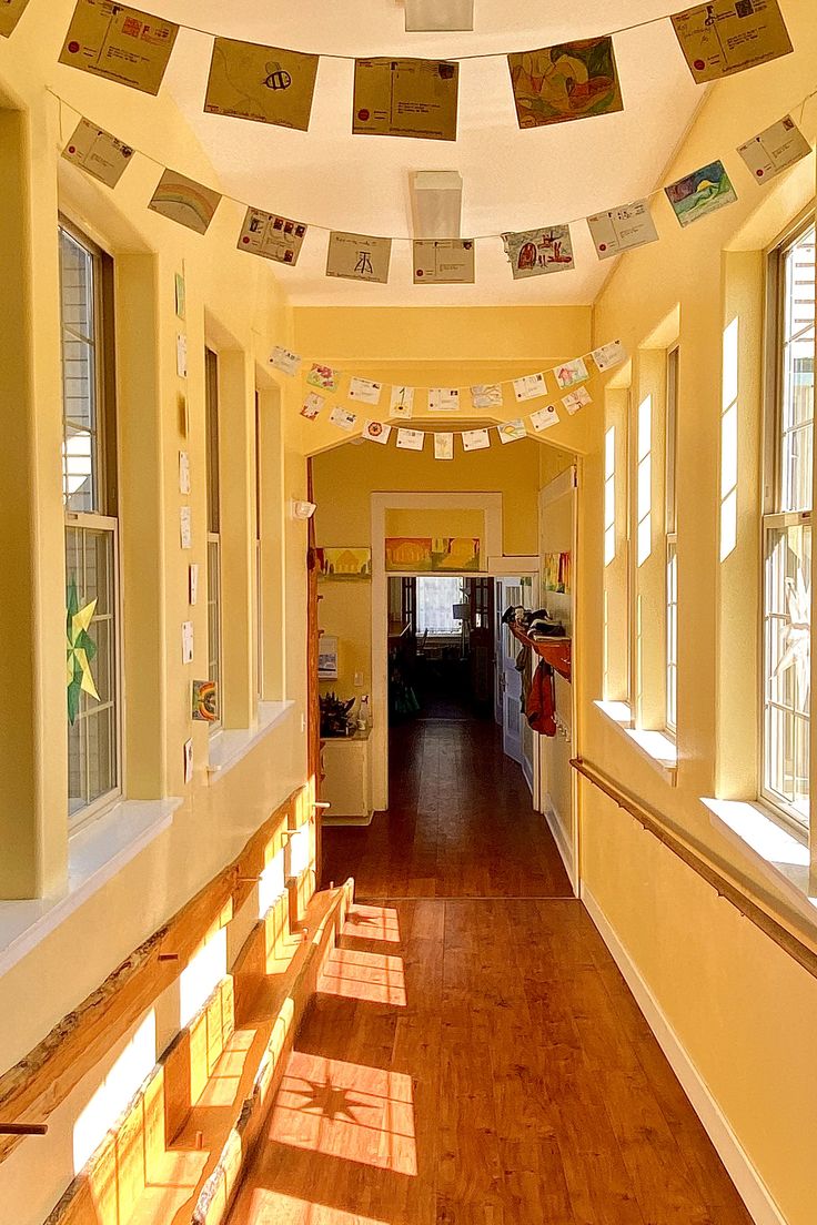 the sun shines through several windows in an empty hallway