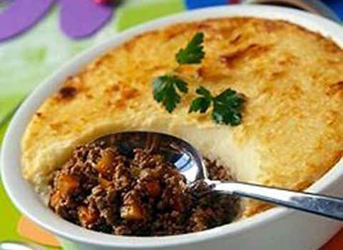 a close up of a casserole dish with meat in it and a spoon