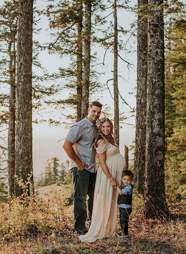 a man and woman standing next to a little boy in the middle of a forest